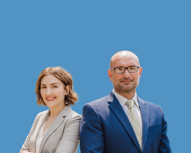 Portrait of Dean Wilhelm Taradash and Morgan Given, partners at Taradash Given, P.C., against a blue background.